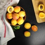 overhead shot of fresh apricots being halved and pitted